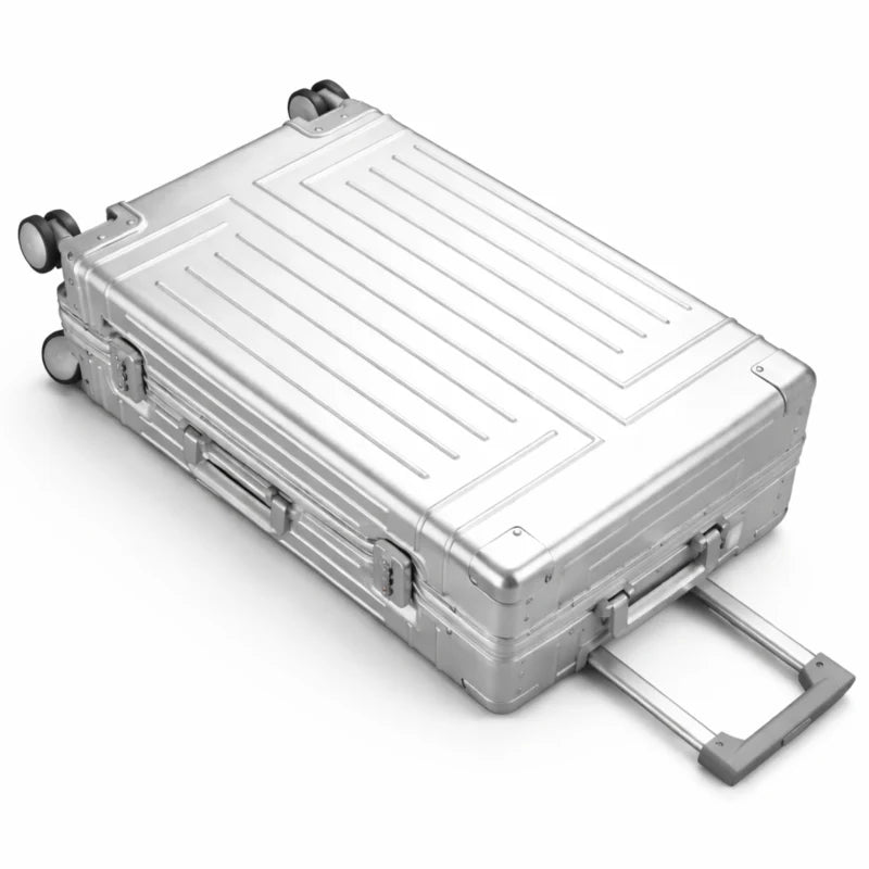 Vue de dessus d'une valise rigide en aluminium argenté avec poignées et roues, prête à être transportée.